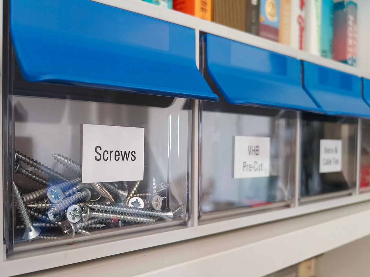 Clear plastic storage bins with screws for organized home workshop setups.